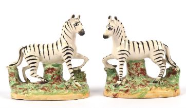 Pair of Staffordshire pottery models of prancing zebra, 19th Century, modelled with tree stump