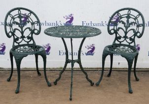 A modern Victorian style green painted metal foliate pierced garden table, on a triform base,
