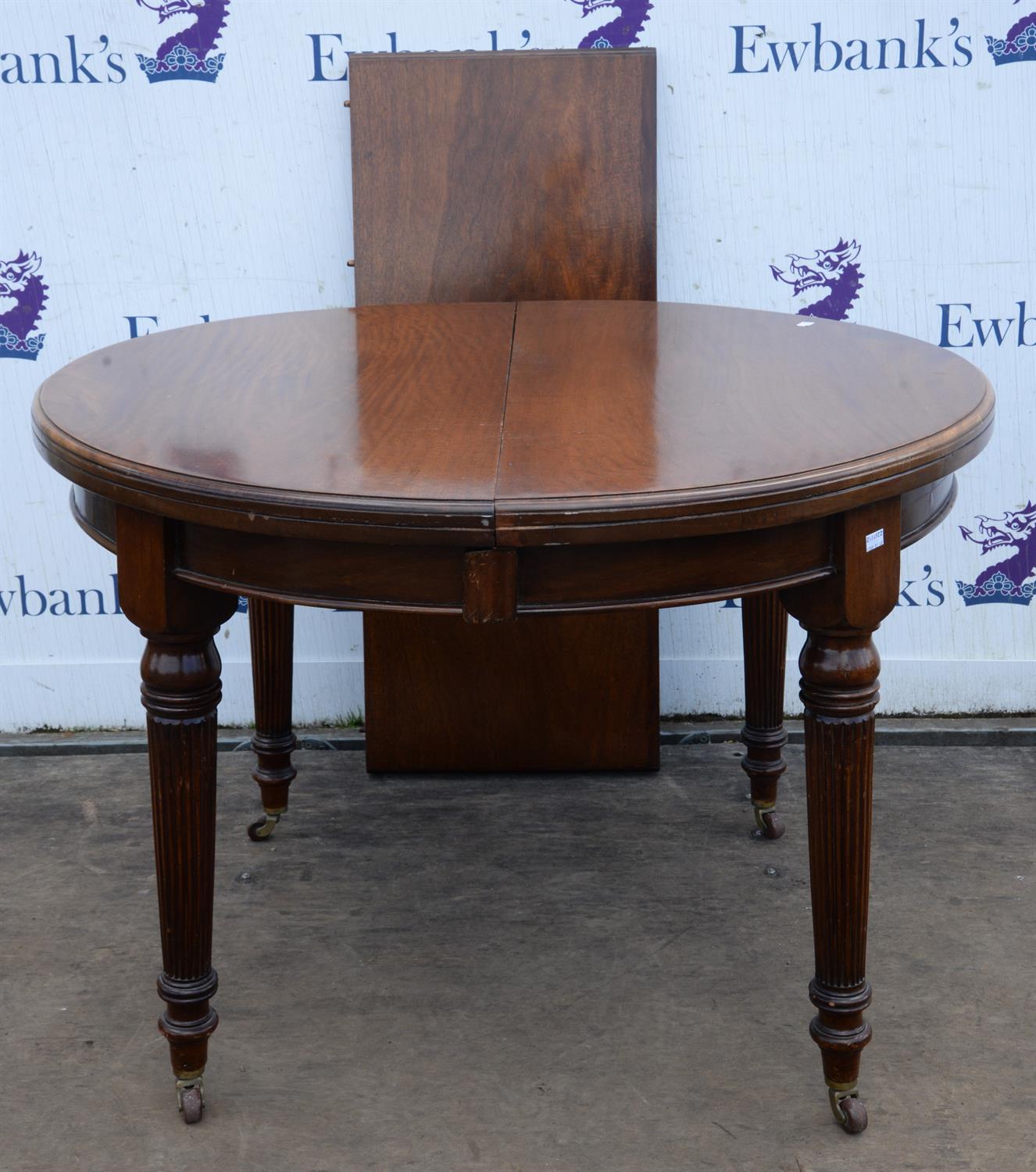 Edwardian mahogany extending dining table, with round top, on fluted legs with ceramic casters,