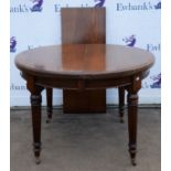 Edwardian mahogany extending dining table, with round top, on fluted legs with ceramic casters,