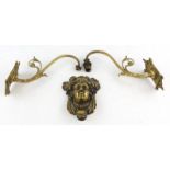 A Late 19th century brass door knocker, relief cast with a female mask beneath a crown of leaves,