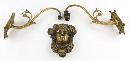 A Late 19th century brass door knocker, relief cast with a female mask beneath a crown of leaves,