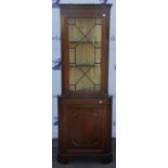 Reproduction mahogany corner cabinet, with glazed door enclosing shelves, on base with panelled