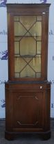 Reproduction mahogany corner cabinet, with glazed door enclosing shelves, on base with panelled