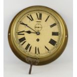 An Edwardian brass wall mounted clock, the 19cm white enamel dial with a winding aperture and