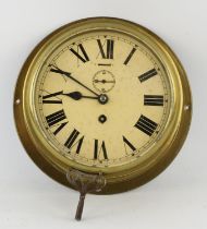An Edwardian brass wall mounted clock, the 19cm white enamel dial with a winding aperture and