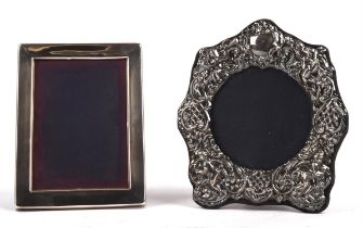 Two silver photo frames, the first embossed and with cherub decoration the second in plain form