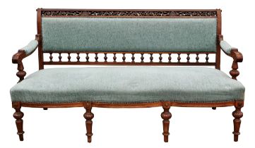 A late Victorian walnut and upholstered settee, the top rail pierced and leaf carved,