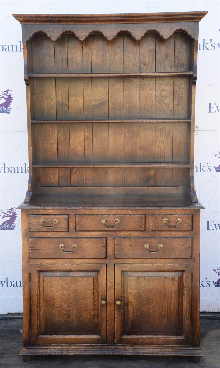 A George III style oak dresser, the rack above a base with an arrangement of drawers and a pair of