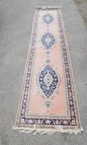 A Turkish pink ground runner, decorated with three blue lozenge within a stylised leaf border,