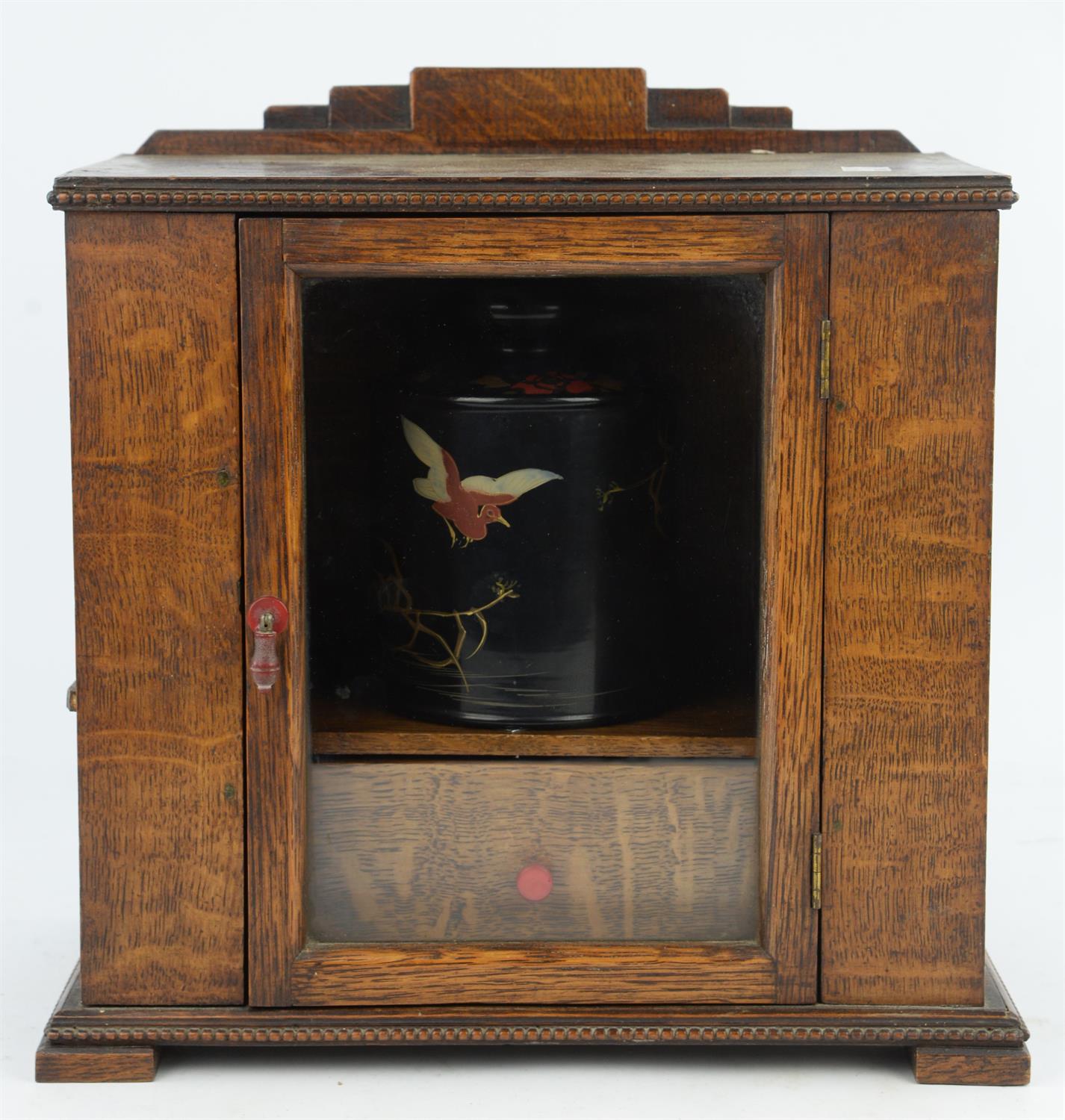 An early 20th century oak smokers cabinet with glazed, hinged door, containing a tobacco box and