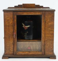 An early 20th century oak smokers cabinet with glazed, hinged door, containing a tobacco box and