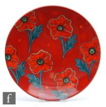 A large later boxed 20th Century Poole Pottery charger decorated with stylised poppies against a red