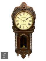 A Victorian carved oak wall clock by L Brunner Birmingham, circular dial over an arched glazed door,