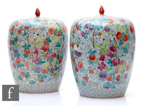 A matched pair of 20th Century Chinese jars and covers, profusely decorated with blossoming flower