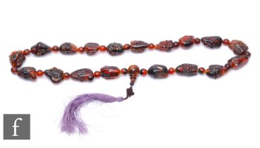 A Chinese late Qing Dynasty carved amber buddha head bead necklace, comprising eighteen carved