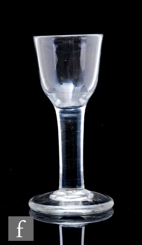 An 18th Century drinking glass circa 1740, the round funnel bowl above a thick plain stem, raised to