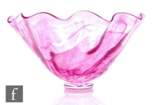 A later 20th Century studio glass bowl, the wave rim body decorated with a mottled pink random strap