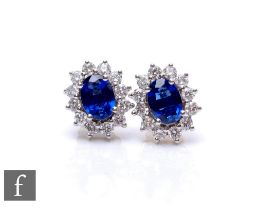 A pair of 18ct hallmarked sapphire and diamond cluster stud earrings, central oval sapphires,
