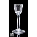 An 18th Century drinking glass circa 1740, the ogee bowl above a slender plain stem, raised to a