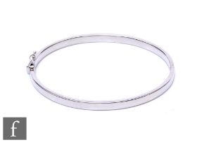 An 18ct white gold hinged bangle of plain form, weight 23g, terminating in tongue and box clasp,