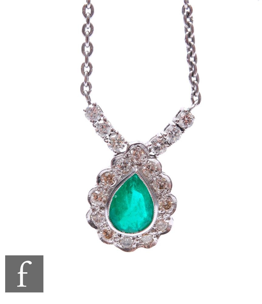An 18ct white gold emerald and diamond pendant, tear shaped emerald within a border of twelve