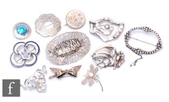 A small parcel lot of assorted silver and white metal brooches to include gold inlaid, stone set and