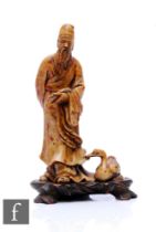 A 19th Century carved soapstone figure of a sage holding a scroll with a swan, on a hardwood base,