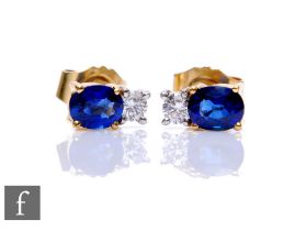 A pair of 18ct hallmarked sapphire and diamond stud earrings, single oval sapphire below a single