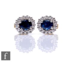 A pair of 18ct sapphire and diamond oval cluster earrings, central sapphire within a diamond set