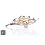 An 18ct white gold spray brooch detailed with six cultured pearl to scroll borders, weight 8.8g,