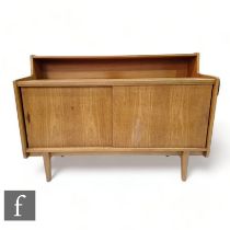 Herbert E. Gibbs - A teak compact cabinet sideboard, with integral ledge shelf above two sliding