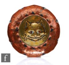 In the manner of Keswick - A small hammered copper dish decorated to the central well with a brass