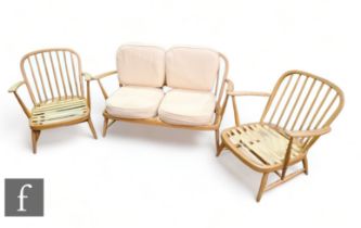 Ercol - A mid Century elm three-piece suite, comprising two Windsor 335 armchairs and two seater