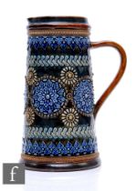 Doulton Lambeth - A large water jug of tapered cylindrical form, heavily decorated with repeat