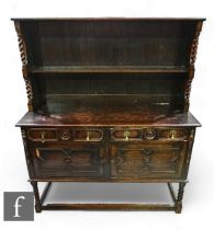 A 17th Century style oak dresser, the single tiered rack and panelled back over a geometric