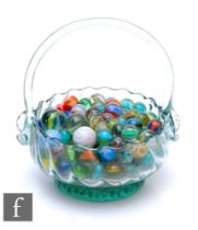 A collection of marbles and a glass basket.