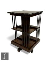 An Edwardian mahogany revolving bookcase, the shaped top over slatted sides, plinth base and