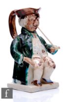 An early 19th Century Toby jug modelled as a seated gentleman in tricorn hat, frock coat,