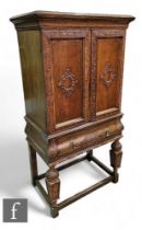 A 1930s Jacobean style carved oak cocktail cabinet, the interior fitted with sliding glazed