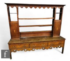 A George III oak dresser, the tiered cupboard rack, flanked by paterae inlaid doors