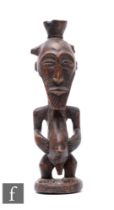 A late 19th to early 20th Century bearded male African fertility figure, standing with hands holding