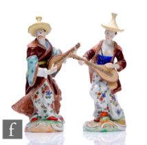A pair of mid 20th Century Dresden figures modelled as Asian musicians in elaborate costume