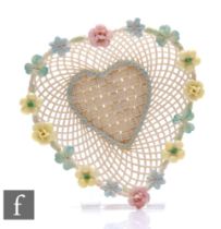 A Belleek heart shaped basket, with ornate flowers to the rim of the basket, applied banner to the
