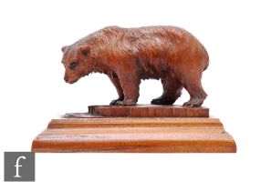 A late 19th to early 20th Century Black Forest carving of a bear fishing for salmon, standing on a