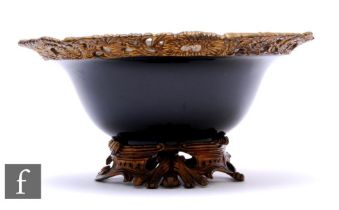 A mid 20th Century black glazed circular fruit bowl with pierced scroll floret border on scroll