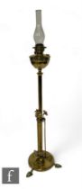 An Art Nouveau brass standard lamp with disc mounts, on a circular base and splayed feet, with glass