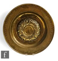 A 16th or 17th Century brass alms dish with raised embossed centre, detailed