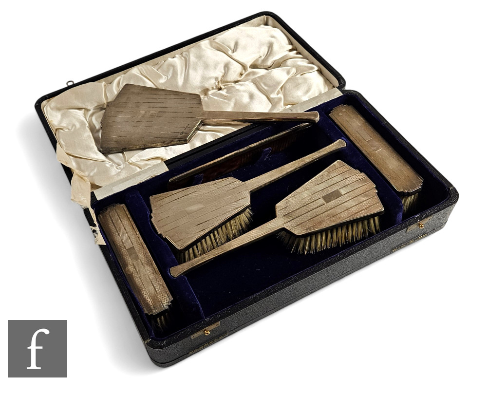 A cased Art Deco hallmarked silver six piece brush set with engine turned decoration to all,