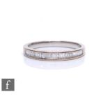An 18ct hallmarked white gold diamond half eternity ring, comprising baguette cut channel set